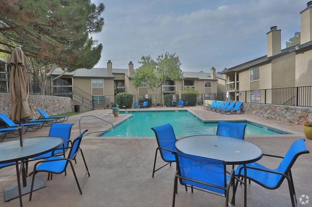 Outdoor swimming pool area with lounge chairs and tables.