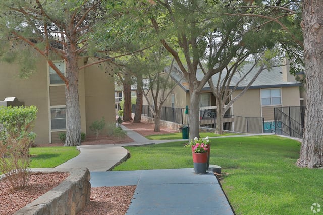 Exterior view of apartment buildings with pathways and trees.