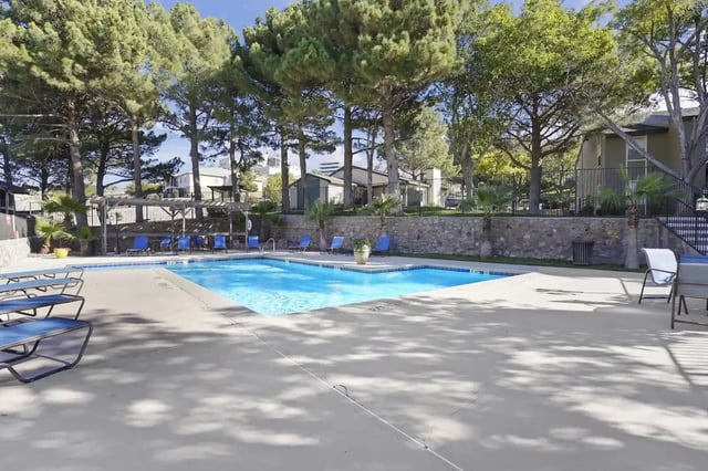 Swimming pool with lounge chairs and trees.