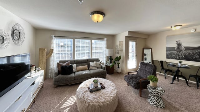 Living room with sofa, ottoman, TV, dining table, and chair.
