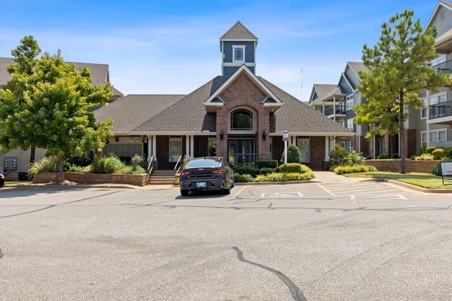 Exterior view of an apartment community entrance with parking and landscaping.