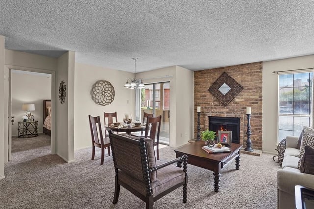 Living room with fireplace, dining area, and view into bedroom.