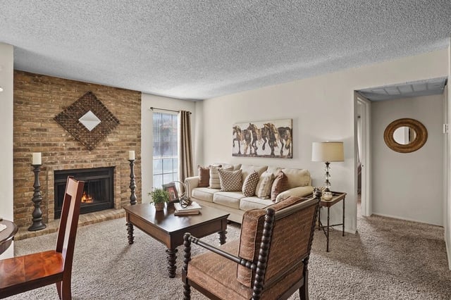 Cozy living room with a brick fireplace, comfortable sofa, and coffee table.