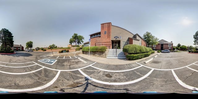 Exterior view of apartment buildings with a parking lot and a sign.