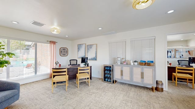 Leasing office with desks, chairs, a coffee station, and view of pool through windows.
