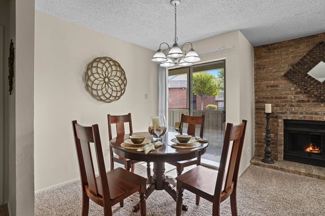 Dining area with round wooden table, four chairs, and a fireplace.
