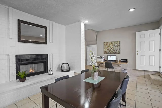 Spacious living area with a fireplace, dining table, and a desk with a computer.