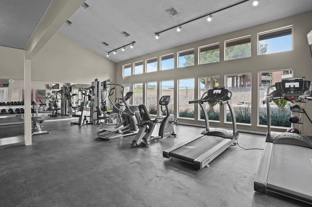 Gym with treadmills, elliptical machines, stationary bikes, and weight racks.