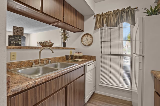 Kitchen with dual sink, countertops, cabinets, dishwasher, and refrigerator.