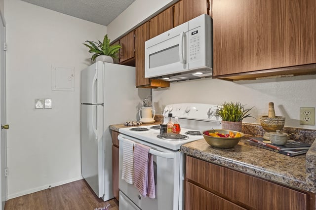 Kitchen with white appliances, wood cabinets, and granite countertops.
