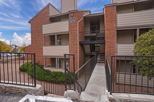 Exterior of apartment building with brick and siding, showing walkways and staircases.