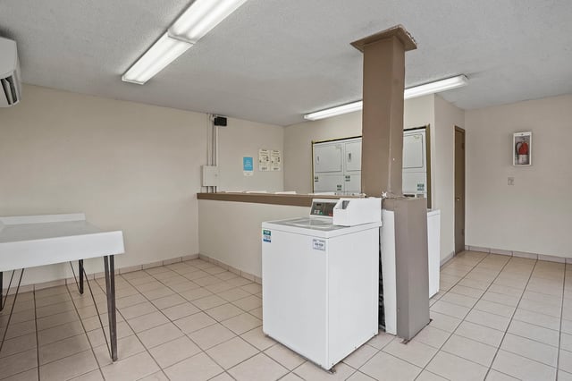 Laundry room with multiple washers, dryers, and a folding table.