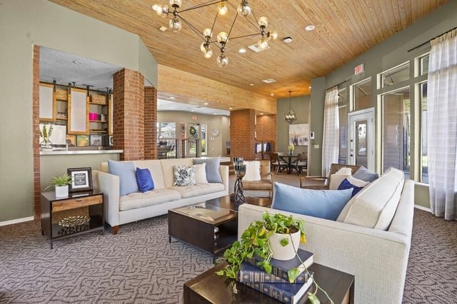 Community lounge with sofas, coffee tables, and wood-paneled ceiling.