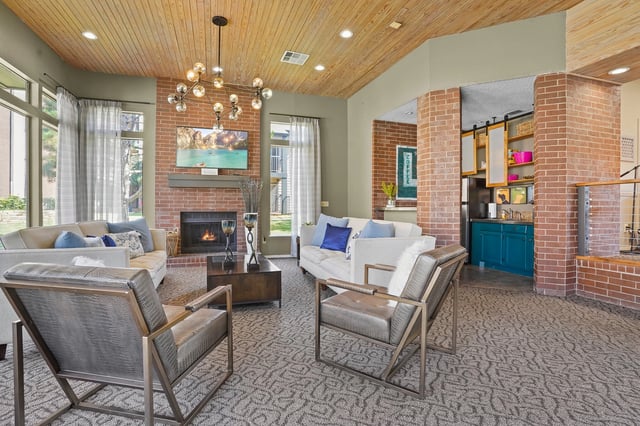 Spacious community lounge with a fireplace, comfortable seating, and a coffee bar area.