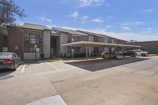 Exterior view of apartment buildings with covered parking and assigned parking spaces.