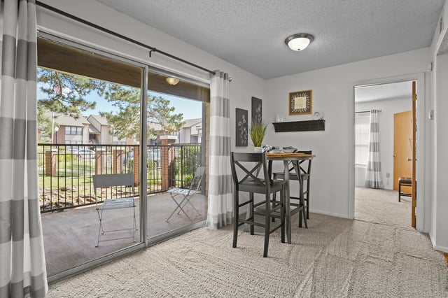 Dining area with high table and chairs and view of balcony and apartment buildings.