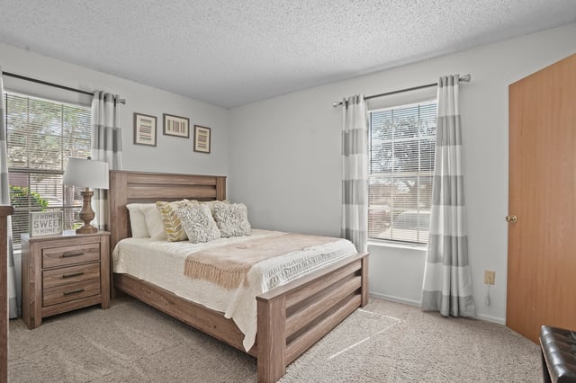 Bedroom with a wooden bed frame, nightstand, and window.