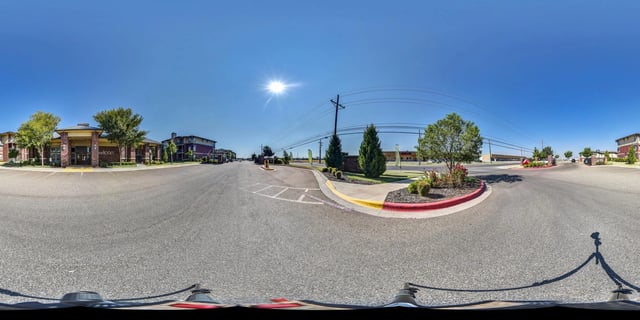 Entrance to apartment complex with brick buildings and trees.