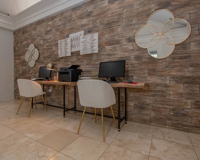 Leasing office workstation with two computers, printer, and stone accent wall.