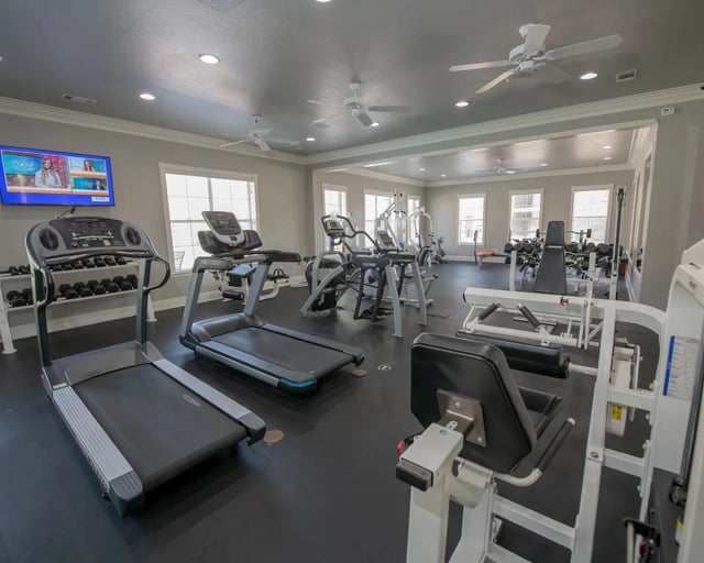 Interior view of a residential building gym with treadmills, weight machines, and benches