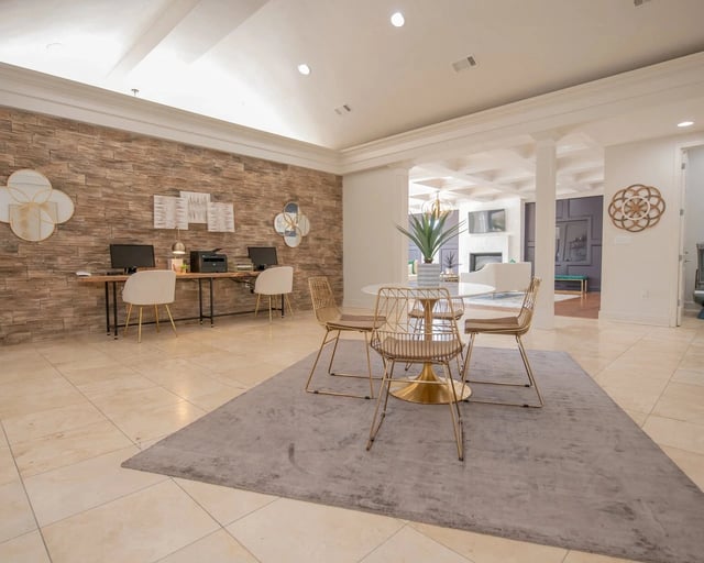 Modern apartment lobby with a stone accent wall, desks, and gold chairs.