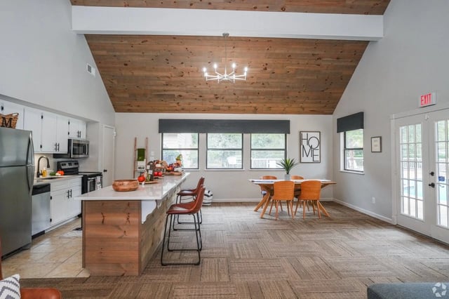 Open communal kitchen and dining area with a wood vaulted ceiling and large windows.