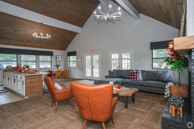 Spacious communal living area with a gray sectional sofa, orange leather chairs, and a central kitchen island.