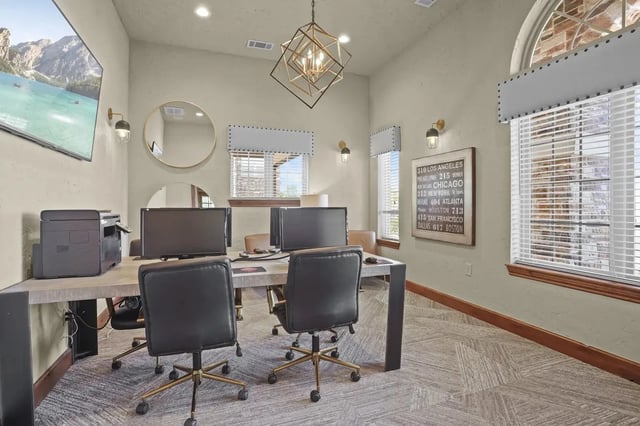 Interior of a communal computer center with desks, monitors, and office chairs.