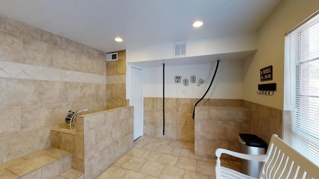 Pet grooming station with tiled walls and floor, bench, and sink.