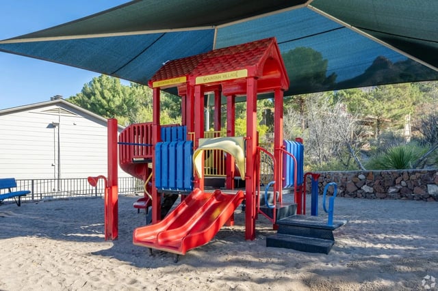 Playground with red and blue structures under a blue sunshade.