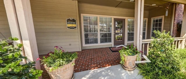 Exterior entrance to apartment building with potted plants and a sign.