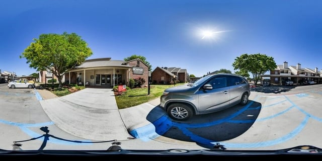 Newport apartment complex entrance with a silver SUV parked in a handicapped spot and apartment buildings in the background.