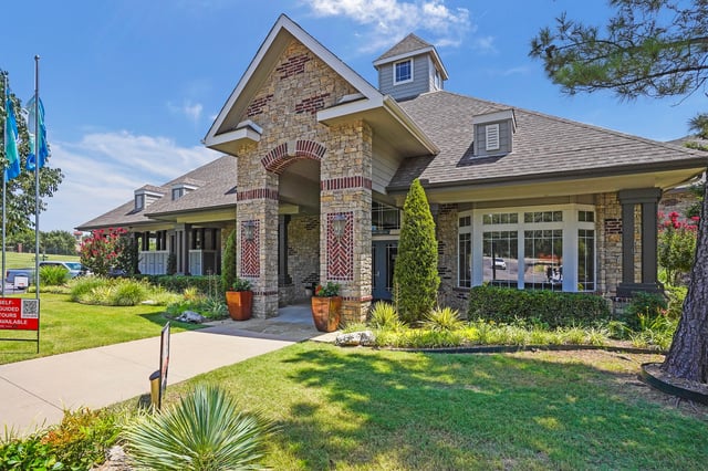 Exterior view of a multifamily property building with stone accents and a manicured lawn.