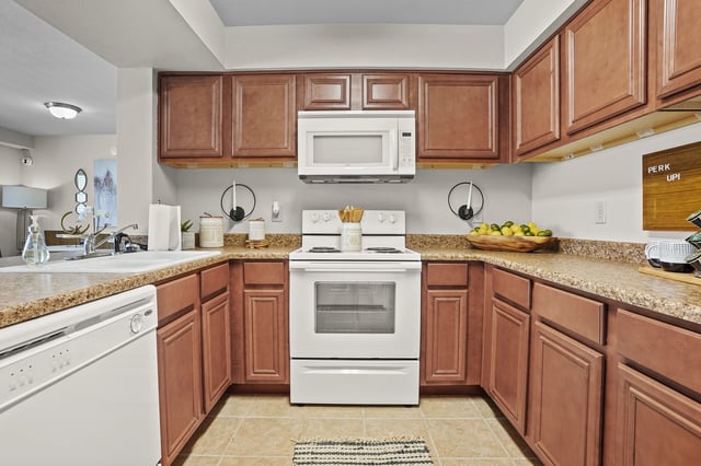 A spacious U-shaped kitchen with wood cabinets, white appliances, and granite countertops.