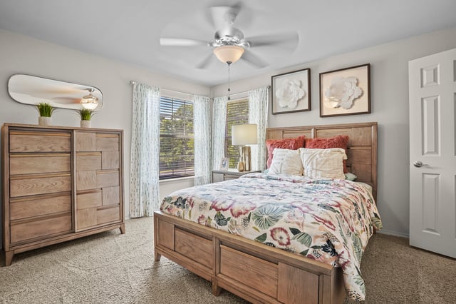 Cozy bedroom with a queen-size bed, dresser, and ceiling fan.