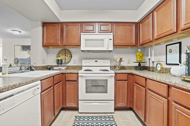 Kitchen with wooden cabinets, white microwave and stove, and granite countertops.