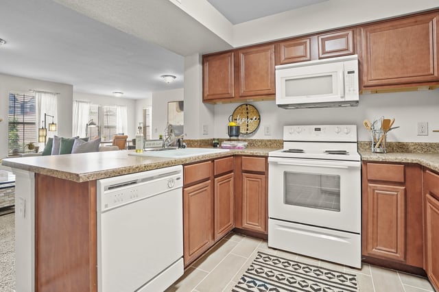 Modern kitchen with white appliances, wooden cabinets, and a granite countertop.