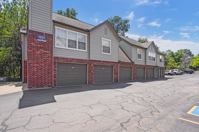 Apartment building exterior with garages and parking lot.