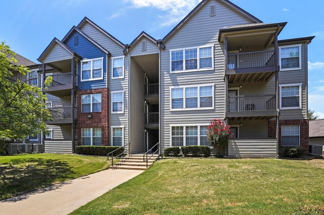 Exterior of apartment buildings with balconies and green lawn.