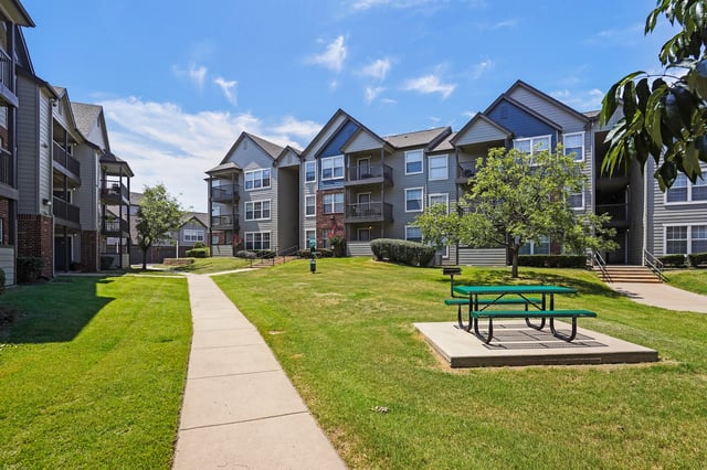 Apartment buildings with a courtyard, pathway, and picnic table.