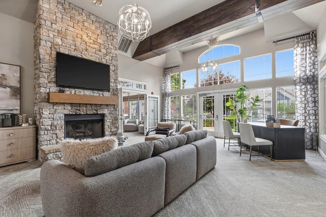 Lounge area with a stone fireplace, comfortable seating, and large windows.