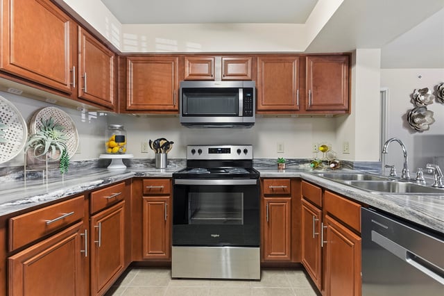 Modern kitchen with cherry wood cabinets, stainless steel appliances, and granite countertops.
