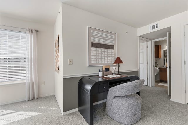 Home office desk and chair with artwork on the wall. View into a bathroom.