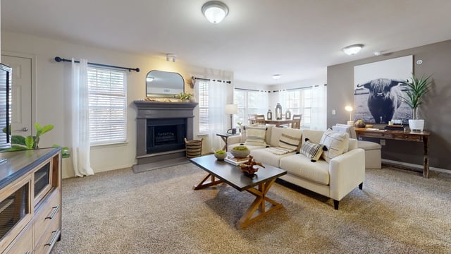 Living room with fireplace, sofa, coffee table, and dining area.