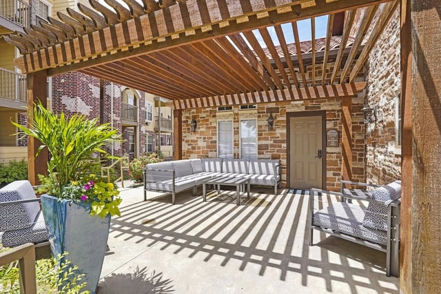 Outdoor seating area with a pergola and stone wall.