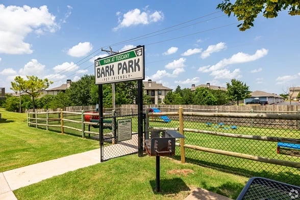 Fenced dog park with a Bark Park sign at an apartment community.