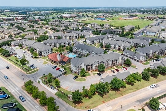 Aerial view of a large multifamily apartment community with many buildings, parking lots, and green spaces.