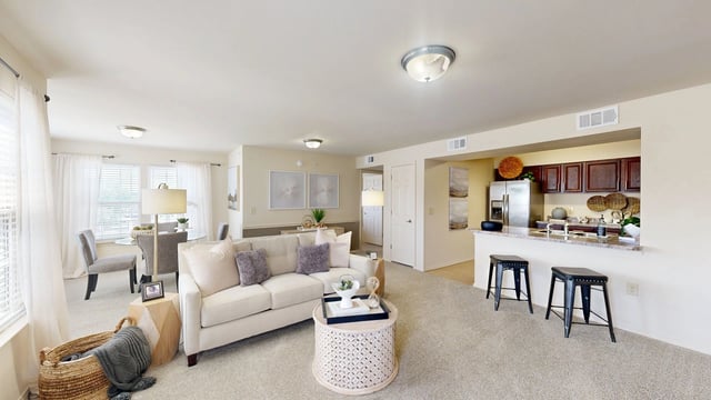 Living room and kitchen area with white couch, coffee table, and breakfast bar with stools.