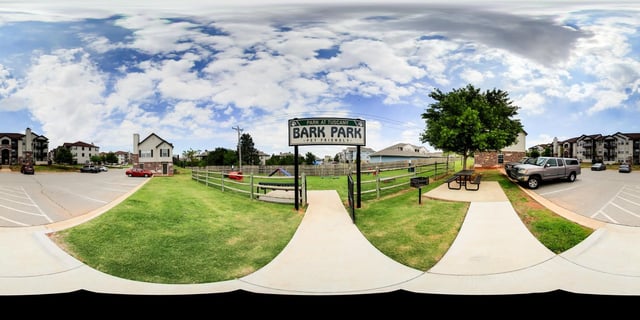 Park at Tuscany Bark Park pet friendly signage and fenced dog park area with green grass.
