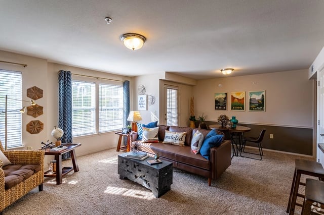 Living room with brown leather sofa, accent chairs, coffee table, and dining table with chairs.
